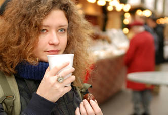 young woman with mulled wine and chestnut at christmass fair